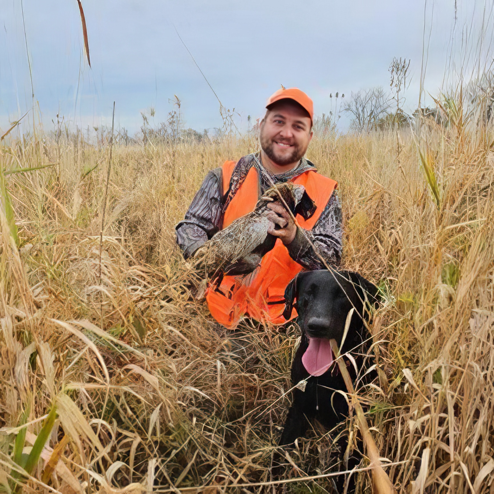 Eddie Bosas Jr. in a public MPHI pheasant field holding a ringnecked pheasant with a black Labradore retriever named Echo
