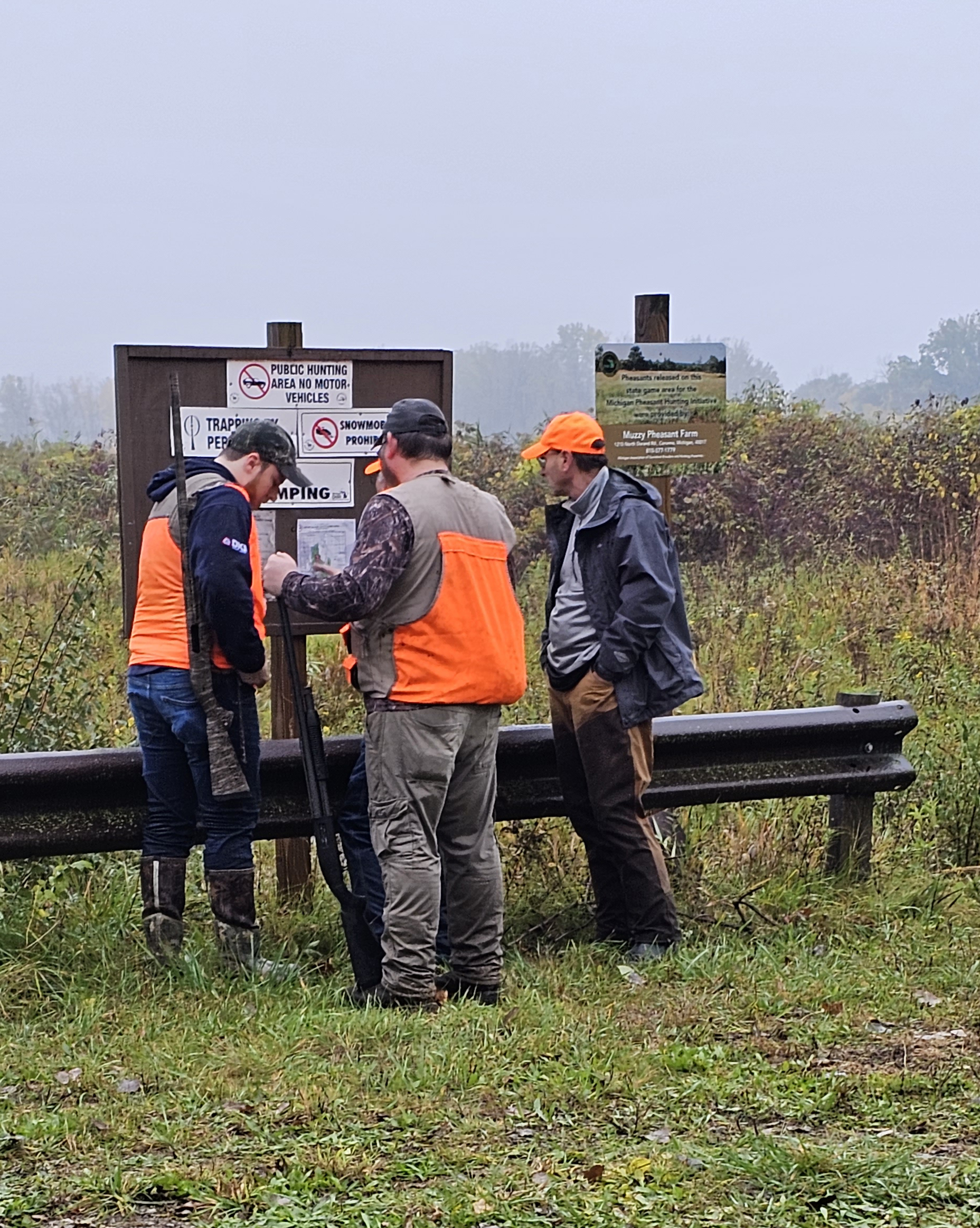 three pheasant hunters gather at the information board at Crow Island State Game Area