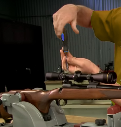 A close-up of hands using a torque wrench to tighten a rifle scope mount screw